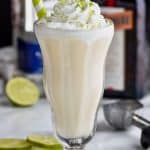 tall milkshake glass filled with margarita boozy milkshake with liquor bottles in the background garnished with lime zest - 7