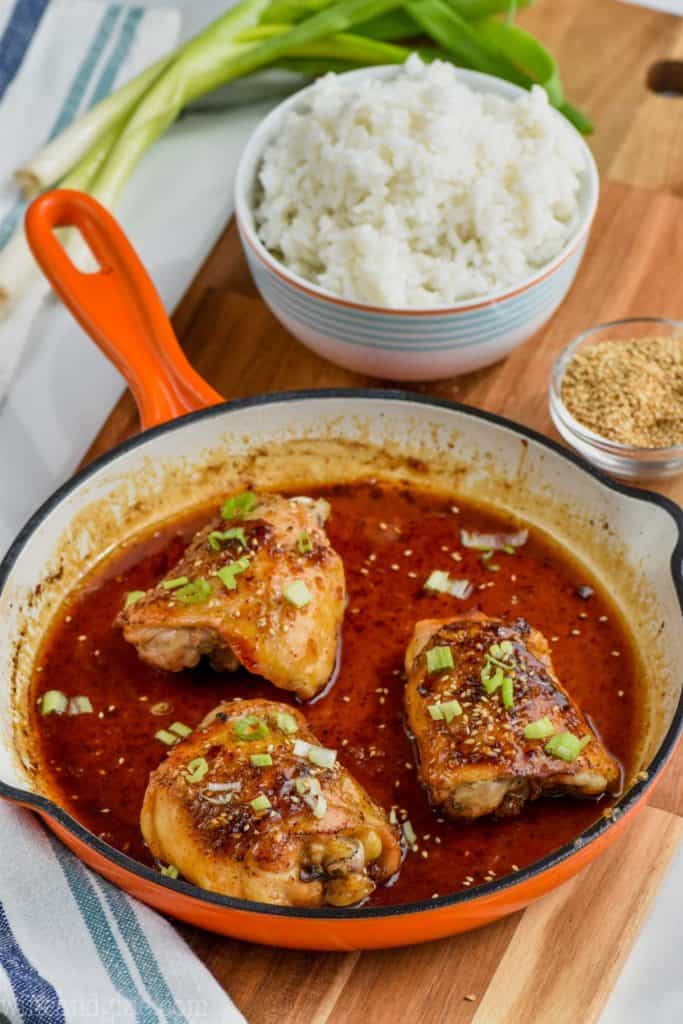 the best honey garlic chicken in a pan with a bowl of rice behind it