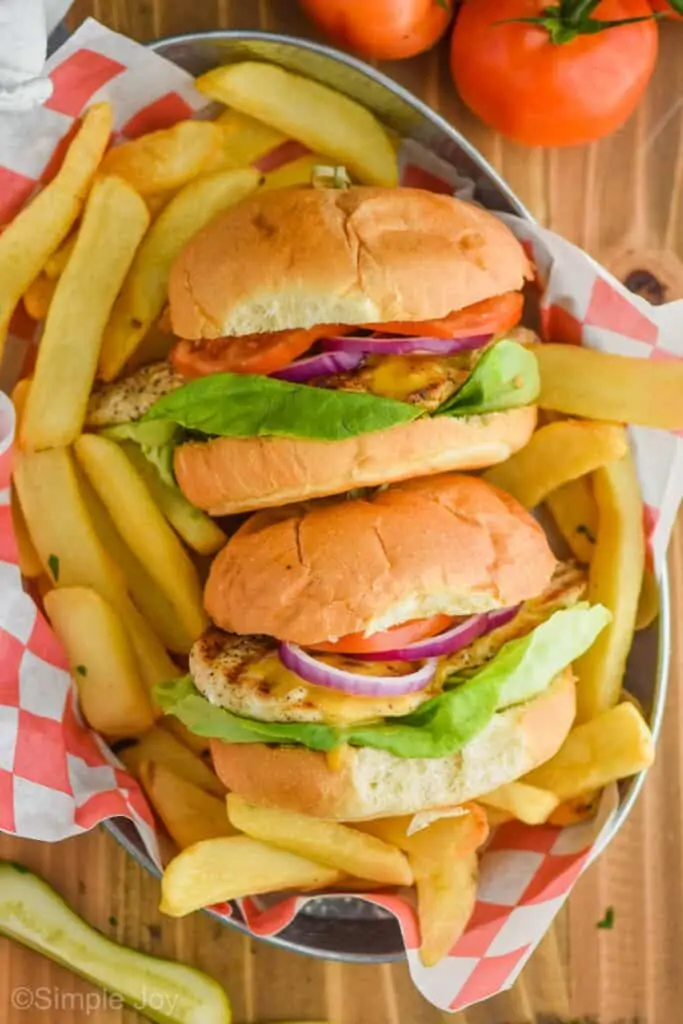overhead view of two grilled chicken sandwiches in a basket with steak fries around them