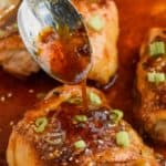 spooning honey garlic sauce over baked chicken thighs in a pan