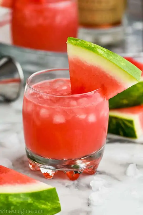 small tumbler full of ice and watermelon vodka tonic, garnished with a watermelon slice