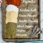 Pinterest graphic of overhead of a baking tray with piles of spices labeled that make up cajun seasoning