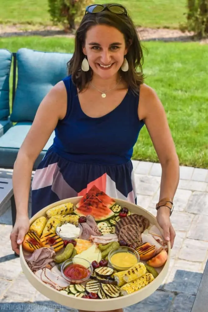 woman holding a giant grilled charcuterie tray 