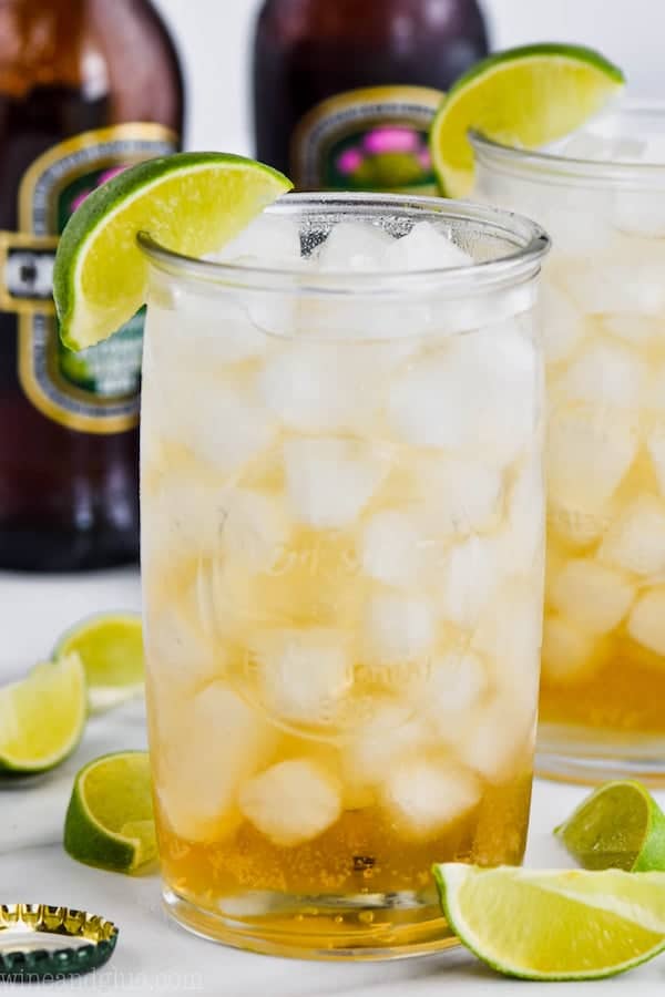 tall glass filled with ice and dark and stormy recipe, garnished with a lime wedge