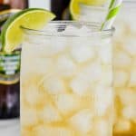 up close view of a tall glass filled with ice and dark and stormy drink with two straws and a lime wedge