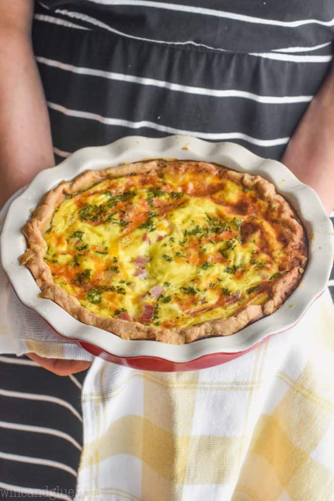 woman holding a ham and cheddar quiche