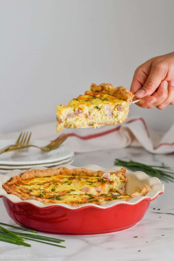 holding a piece of quiche over a pie plate