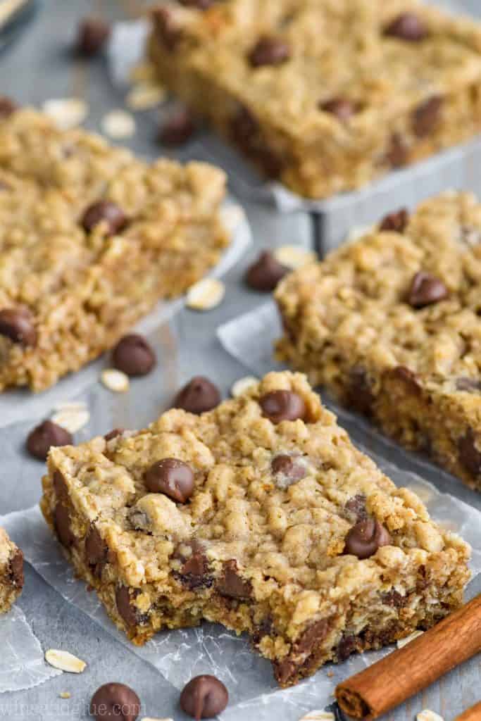 Close up photo of the Oatmeal Chocolate Chip Bars with a small bite in them and a parchment paper underneath