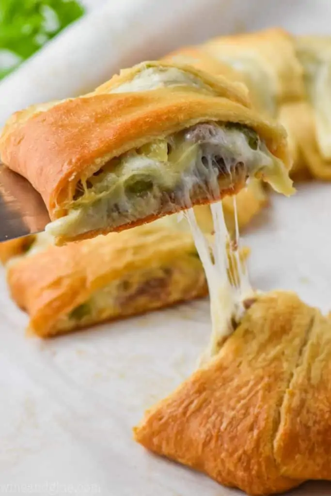 piece of a philly cheese steak crescent ring being pulled off a pan