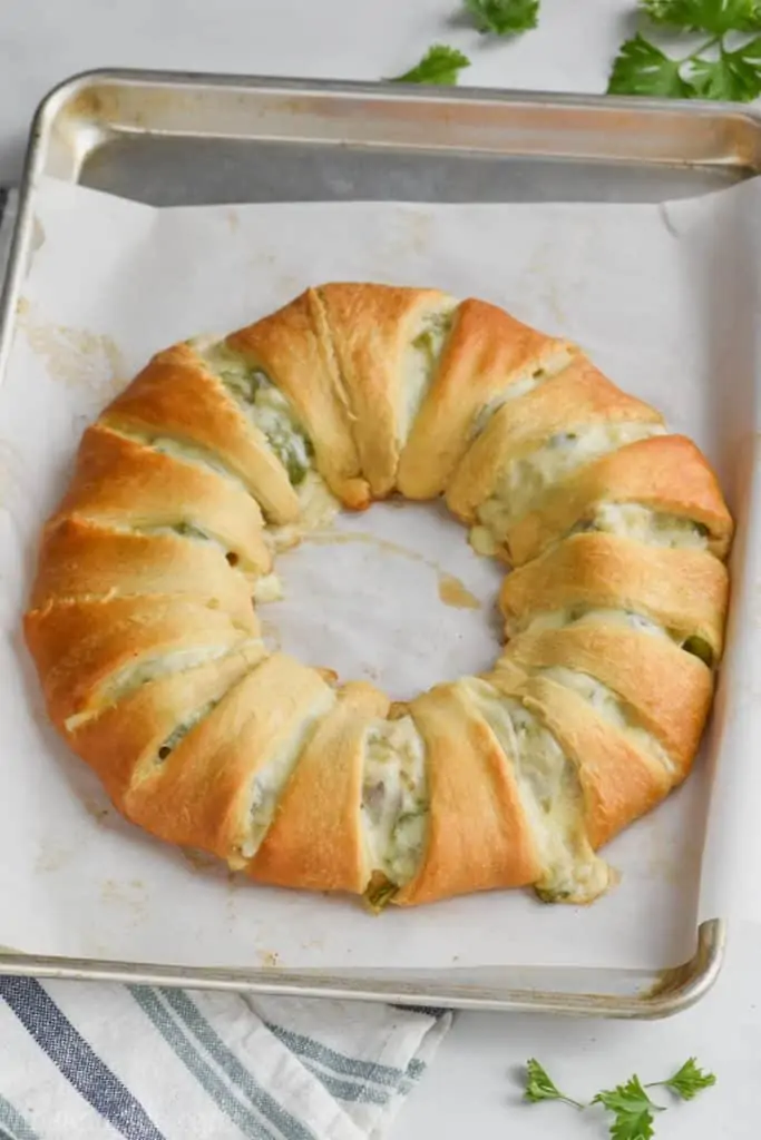 baked philly cheese steak crescent ring on a baking sheet with a golden brown crust and cheese oozing out