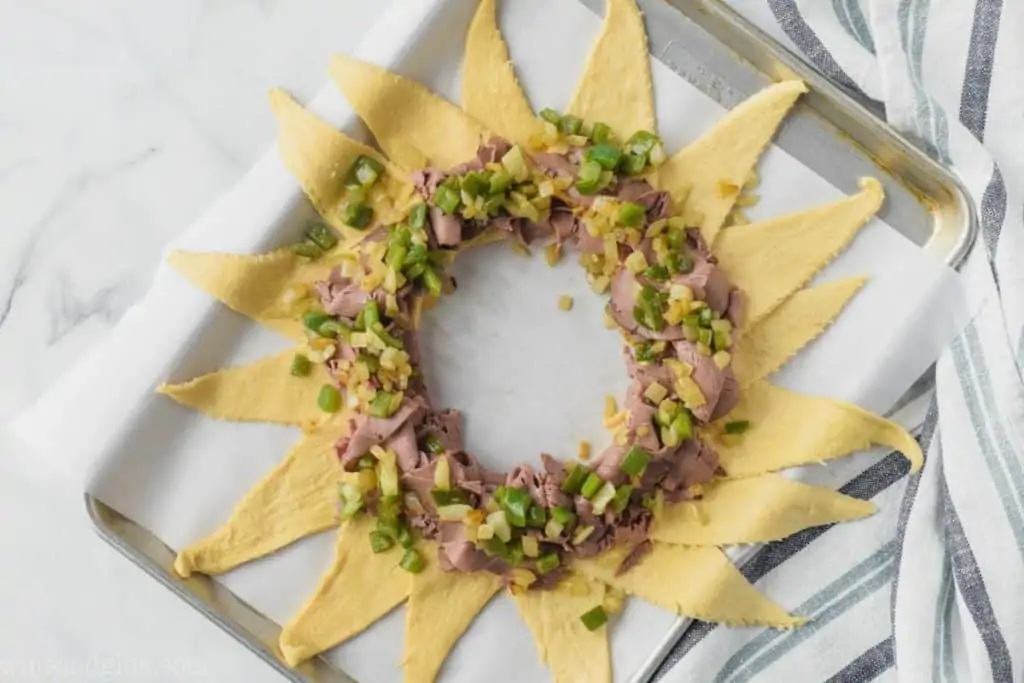 crescent roll dough with deli roast beef, green peppers, and onions