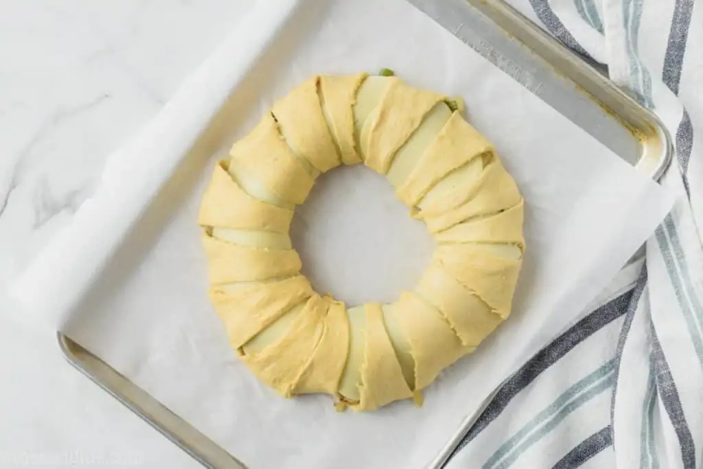 a Philly Cheese Steak crescent ring on a baking sheet with the long sides of the triangle wrapping the filling in