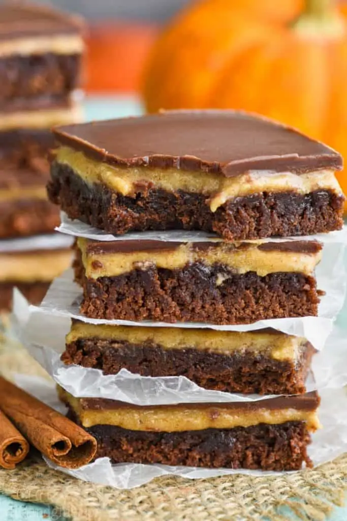 A stack of four of the best pumpkin brownie recipe with parchment paper underneath each one