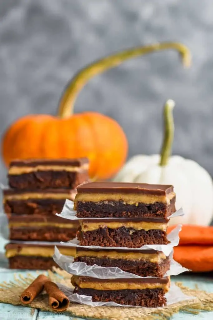 two stacks of pumpkin chocolate brownies with pumpkins in the background