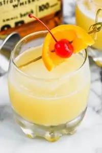 the best whiskey sour recipe garnished with an orange and cherry