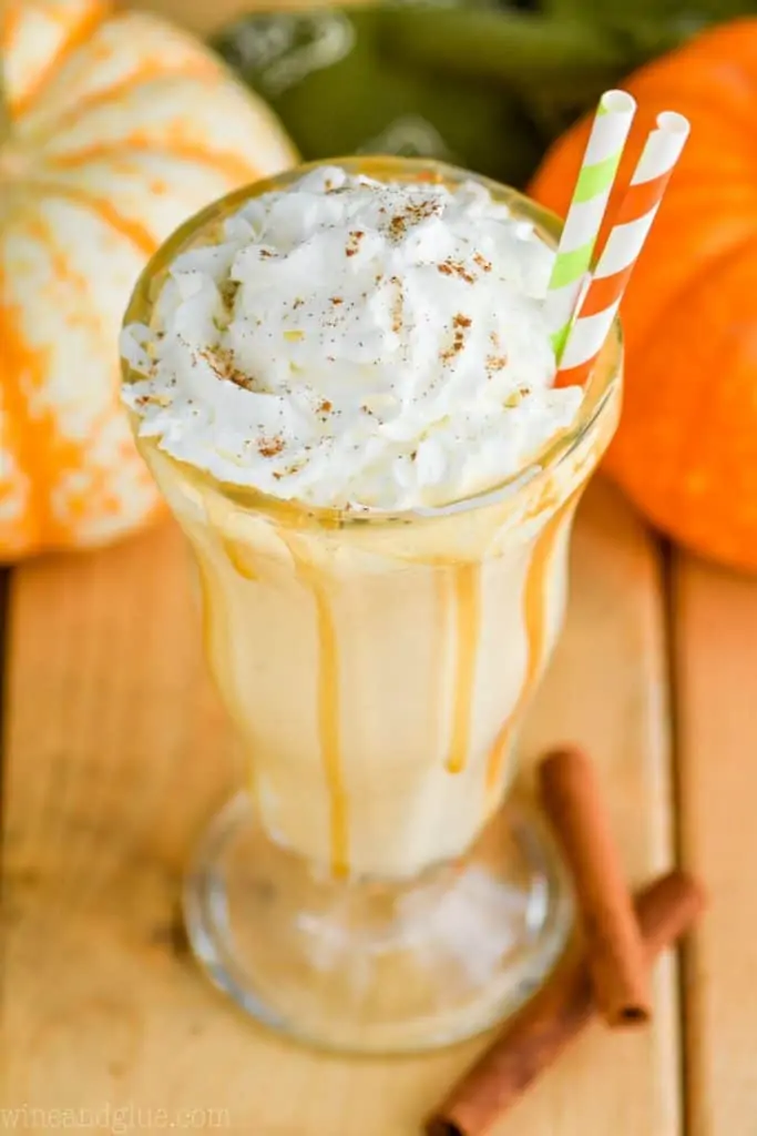 overhead view of boozy pumpkin milkshake with whipped cream and straws
