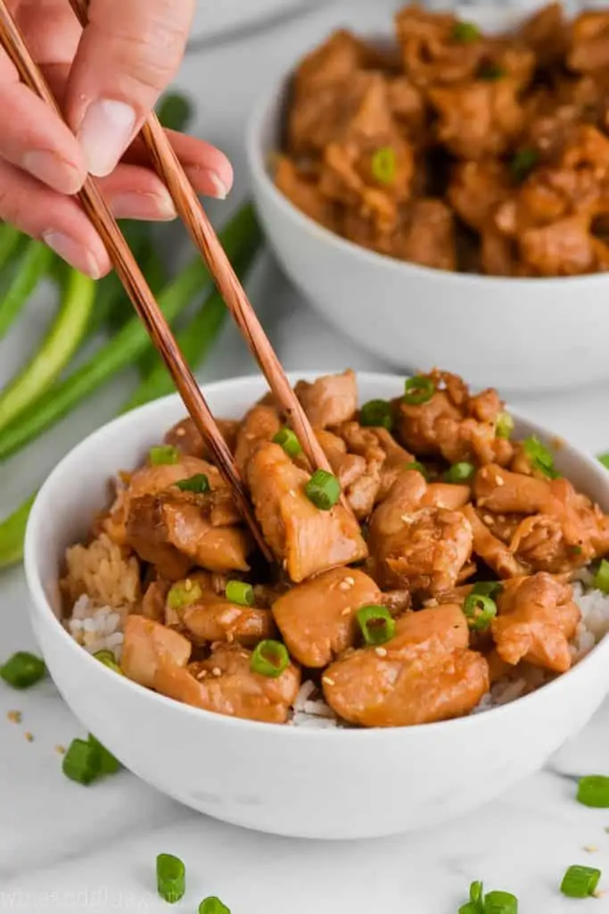 chopsticks picking up a piece of bourbon chicken like food court