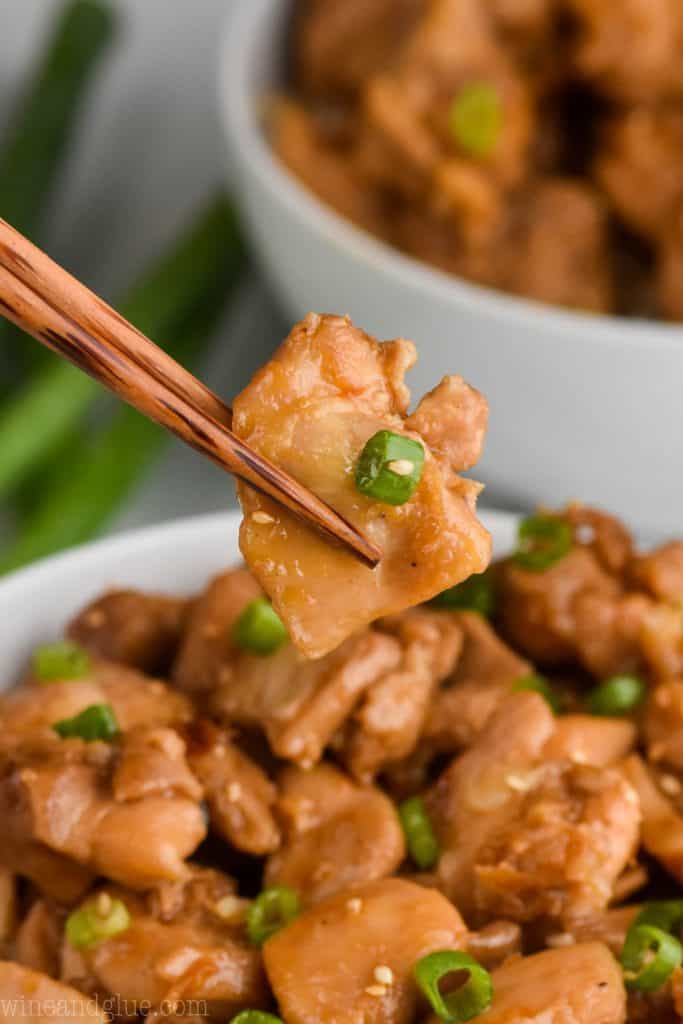 a closeup photo chopsticks holding a piece of the best bourbon chicken