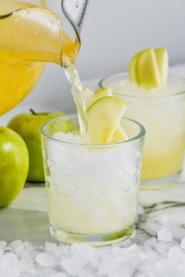 cup of caramel apple vodka punch garnished with sliced apples