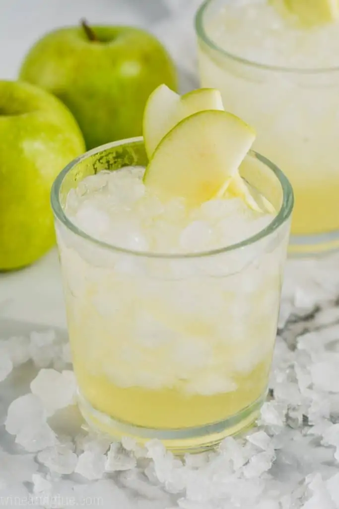 cup of caramel apple vodka punch garnished with sliced apples