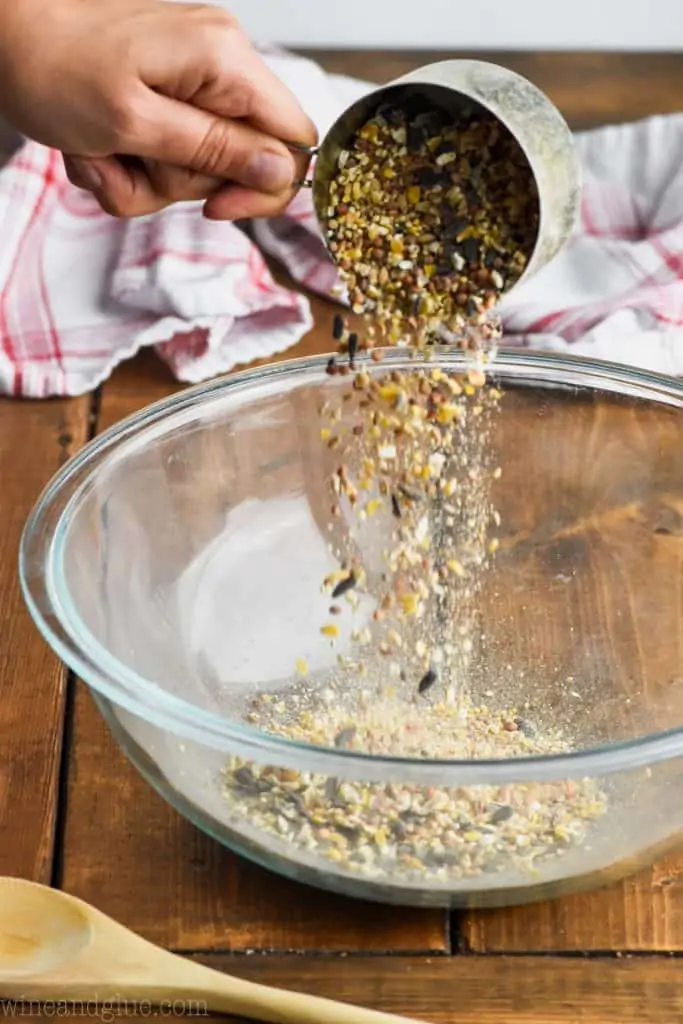 birdseed being poured into a bowl to make easy diy bird feeders
