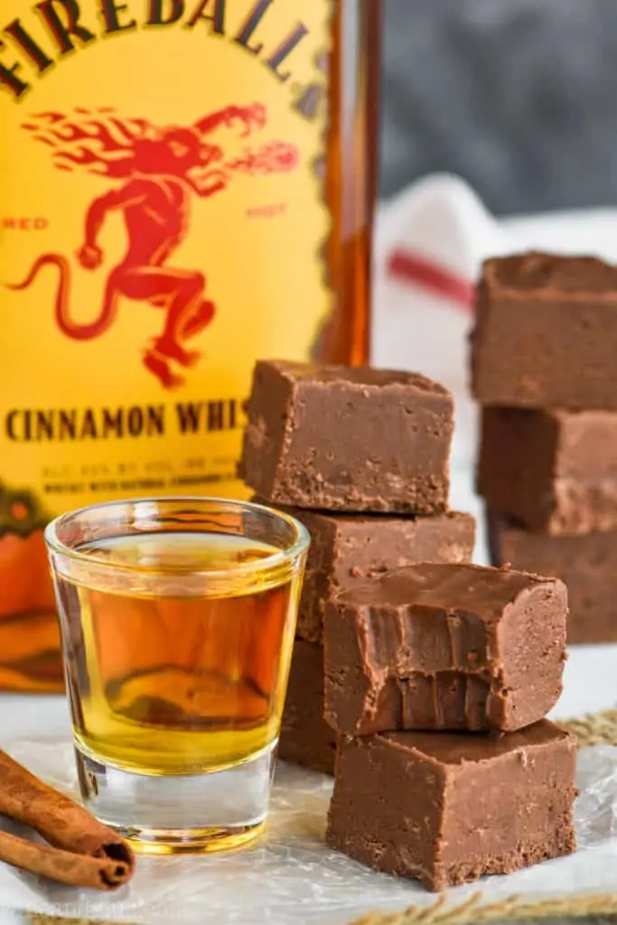 A small stack of the Fireball Fudge next to a shot glass full of fireball. The top piece has a small bite. 