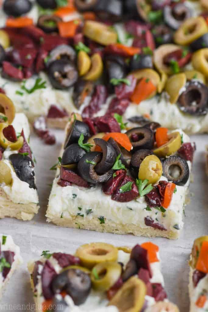 piece of olive pizza amongst the rest of the pieces with black, green, and kalamata olives