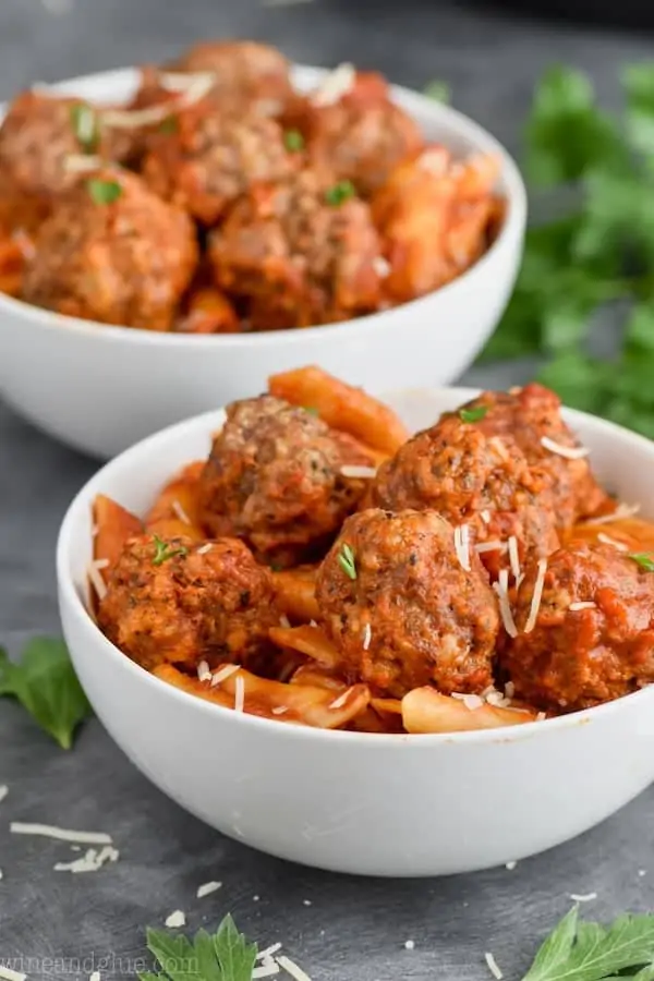 close up of a white bowl of pressure cooker meatballs and pasta garnished with parsley