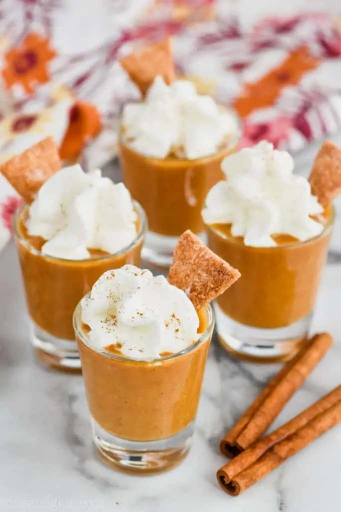 shot glass full of pumpkin pie shot topped with whipped cream and pie crust