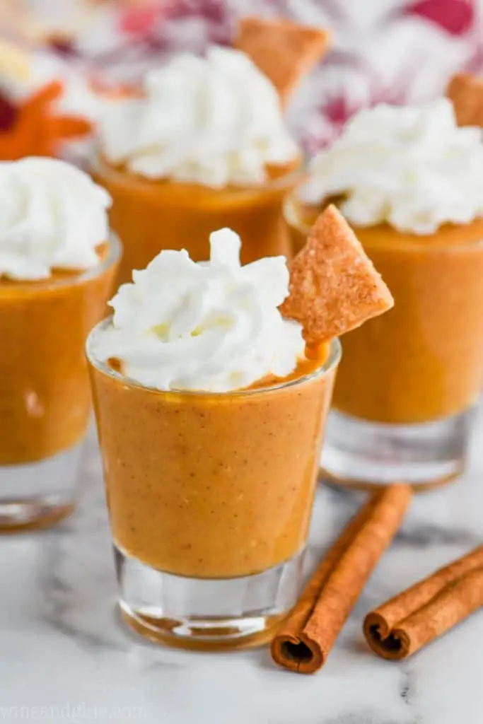 shot glass full of pumpkin pie shot topped with whipped cream and pie crust