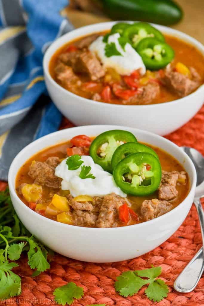 side view of a bowl of steak fajita soup that is topped with sour cream, cilantro, and jalapenos.