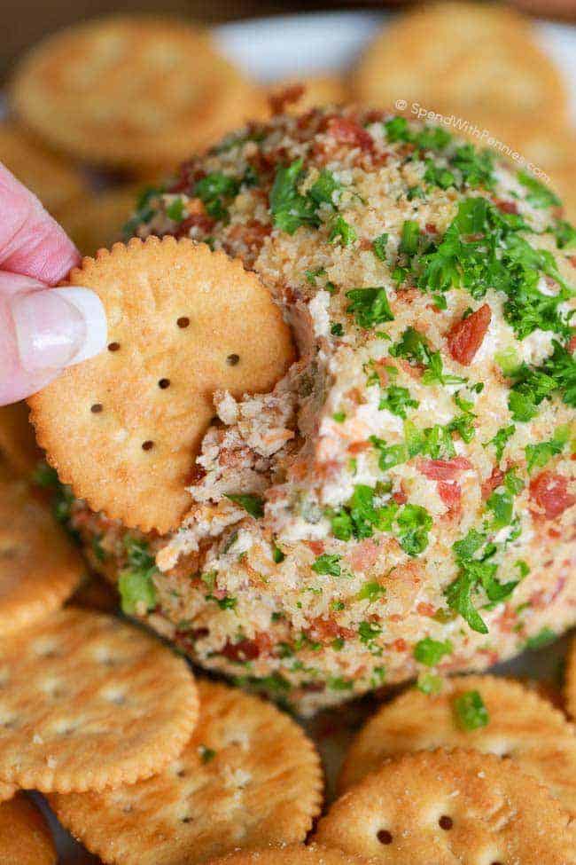 A closeup photo of the Bacon Jalapeno Cheese Ball in which a Ritz Cracker is digging in. 