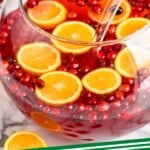 pinterest graphic of close up of a punch bowl with christmas punch with alcohol with floating fresh cranberries and orange slices, says: "christmas punch simplejoy.com"