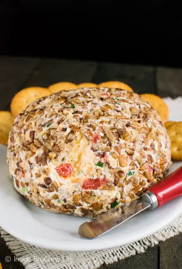 In the middle of the plate, a Roasted Red Pepper and Garlic Cheese Ball has a small slice cut out. 