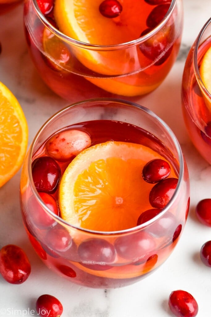 close up of glass of alcoholic christmas punch with a floating orange slice and fresh cranberries