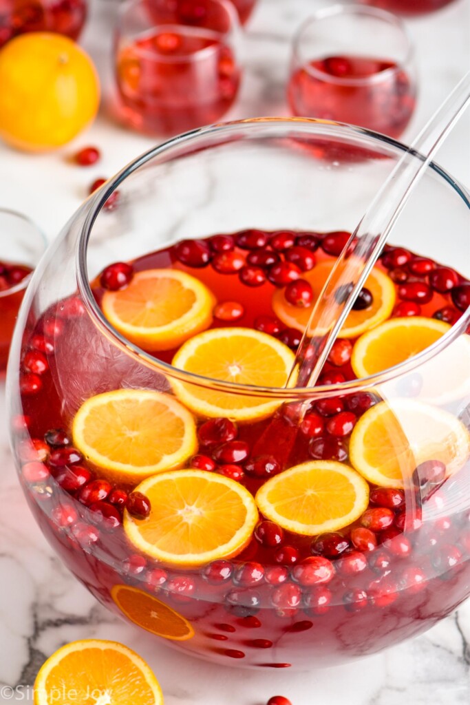 close up of a punch bowl with christmas punch with alcohol with floating fresh cranberries and orange slices