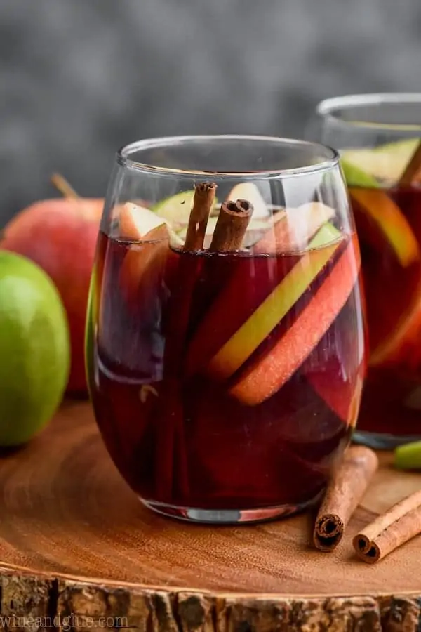 glass of cinnamon whiskey sangria filled with apple slices and cinnamon sticks