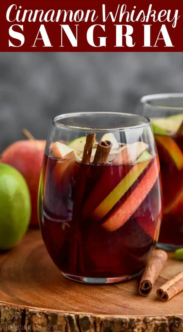 glass of cinnamon whiskey sangria filled with apple slices and cinnamon sticks