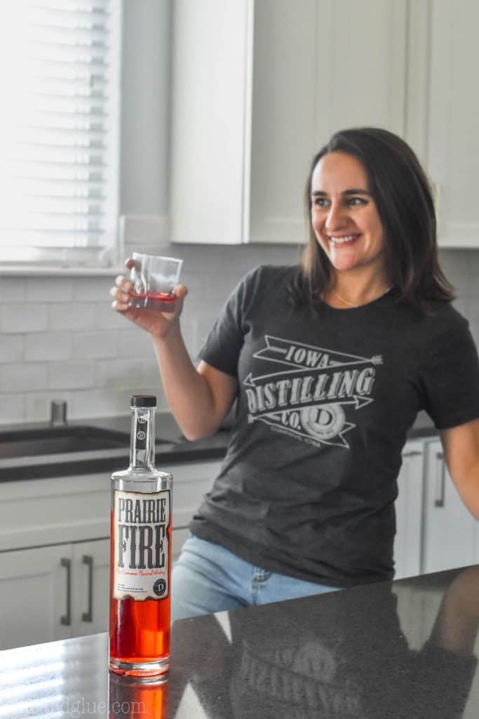 woman standing in a kitchen with a bottle of cinnamon whiskey