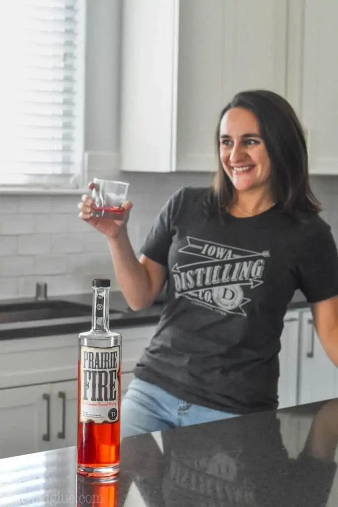 woman standing in a kitchen with a bottle of cinnamon whiskey