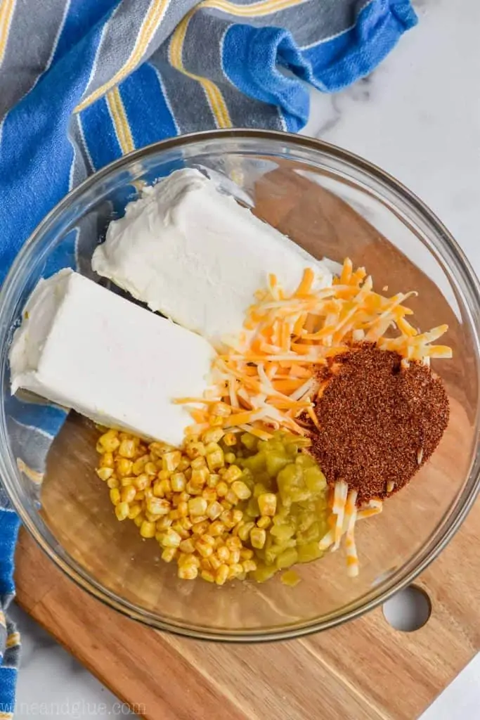 overhead view of ingredients (Cream Cheese, Corn, Taco Seasoning, Cheese, and green chilies) for easy taco cheese ball recipe
