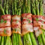 four groups of bacon wrapped asparagus baked with brown sugar on a tray