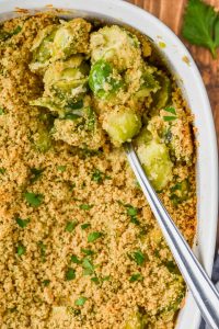overhead view of baked brussel sprouts casserole in casserole dish being spooned out