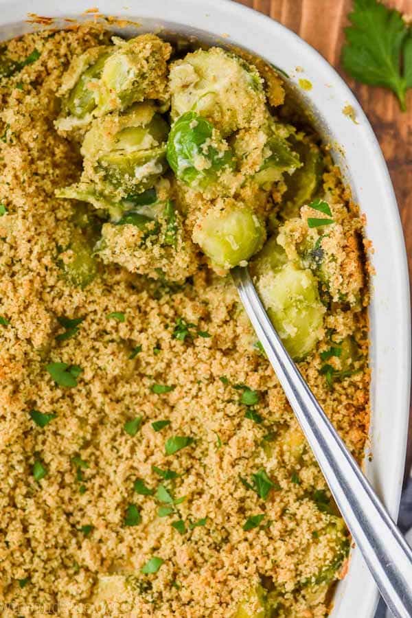 overhead view of baked brussel sprouts casserole in casserole dish being spooned out