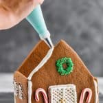 piping gingerbread icing on a built gingerbread house recipe