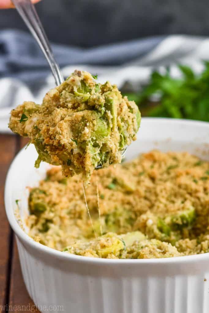 oven baked brussels sprouts being spooned out of a white casserole dish
