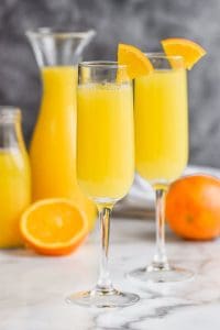 two mimosa mocktails garnished with oranges wedges