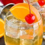 glass of amaretto sour garnished with a cherry and an orange slice