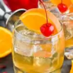 small tumbler with amaretto sour recipe garnished with an orange slice and cherry