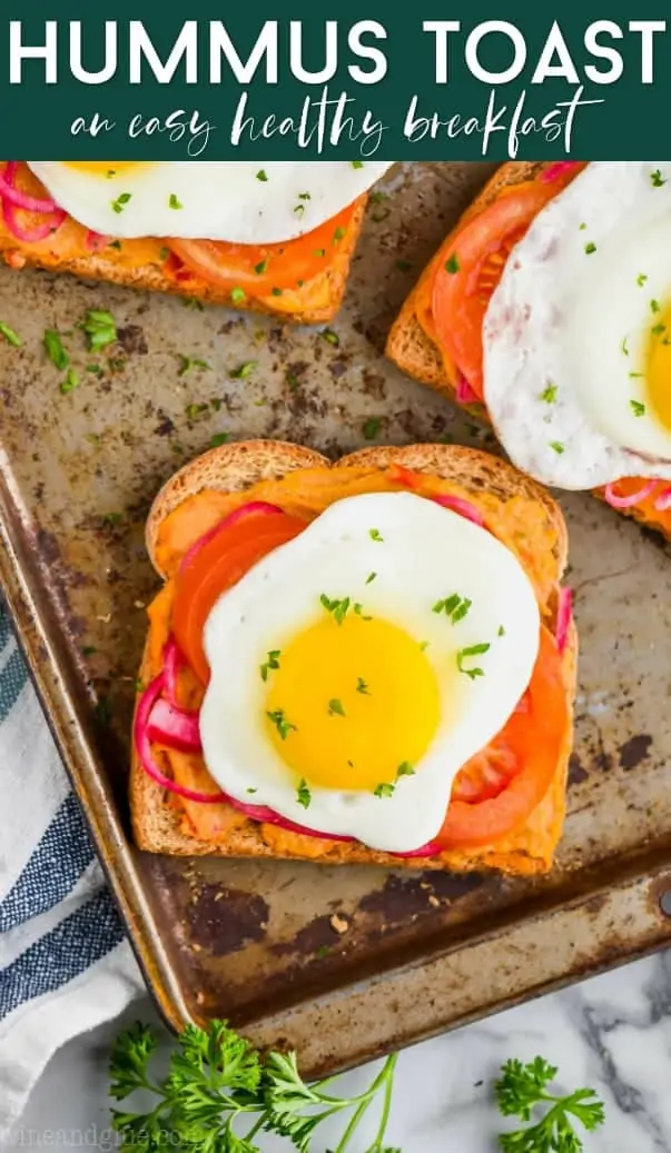 hummus toast layered with pickled red onions, tomatoes, and a fried egg